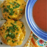 square photo of cheese toasts with pickle and a bowl of tomato soup