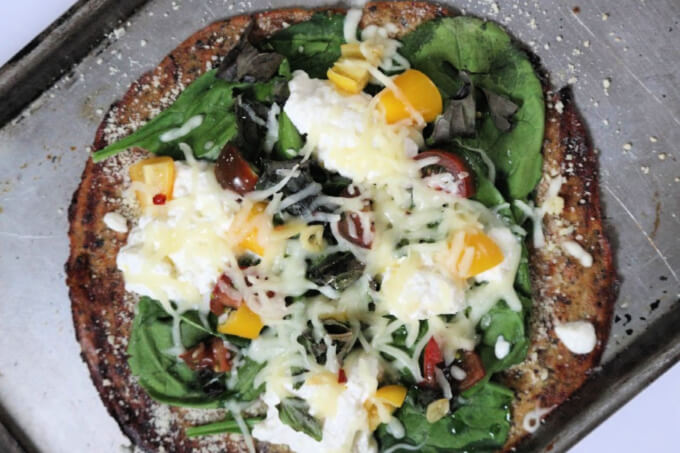 photo of finished pizza with homemade ricotta plus greens, cherry tomatoes, onions and yellow bell peppers