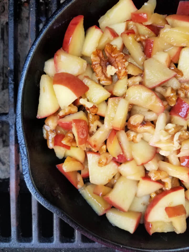 apples and walnuts cooking in a cast iron skillet on a grill
