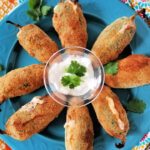 plateful of jalapeno poppers arranged around a dish of sour cream
