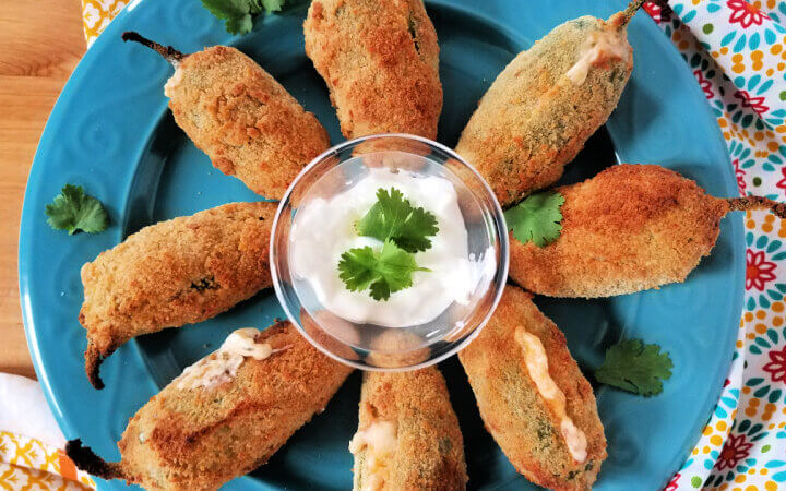 plateful of jalapeno poppers arranged around a dish of sour cream